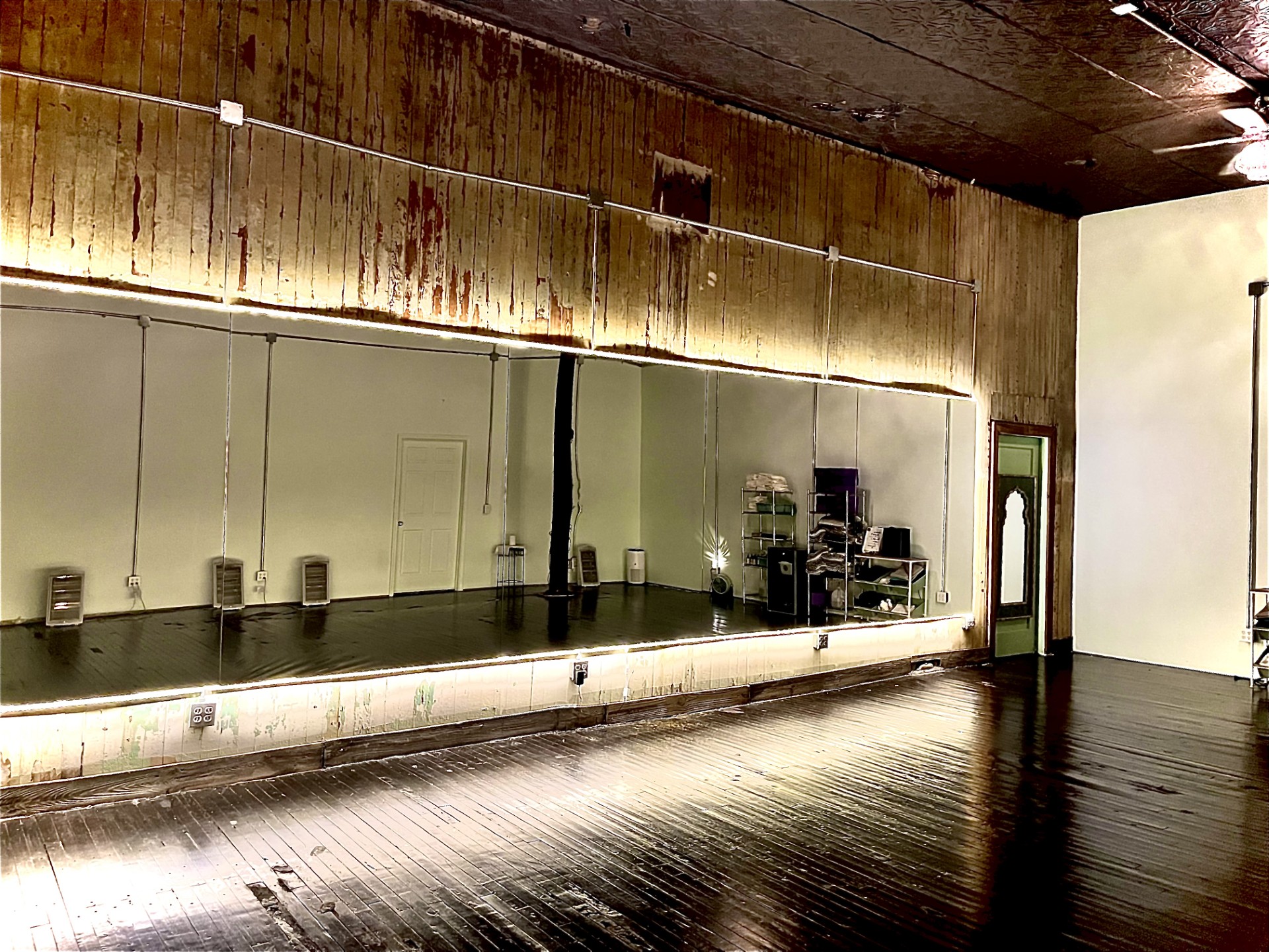 The main practice room at Yoga on Main with mirrored wall and dark wood floors